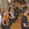 Vestidos de negro, la gente se sienta con las piernas cruzadas y medita en una habitación luminosa, abrazando el bienestar a través de Clases de Yoga Terapéutico en Granada: bienestar para cuerpo y mente. - ForTwo - Planes para parejas