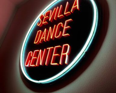 Un vibrante letrero de neón brilla suavemente en una pared tenue, anunciando el Sevilla Dance Center: Academia de baile urbano en el corazón de Sevilla. - ForTwo - Planes para parejas