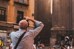 Alguien está involucrado en el Taller de Fotografía en Granada: aprende a dominar tu cámara réflex, capturando imágenes de un edificio histórico que se eleva sobre la animada multitud que se encuentra debajo. - ForTwo - Planes para parejas