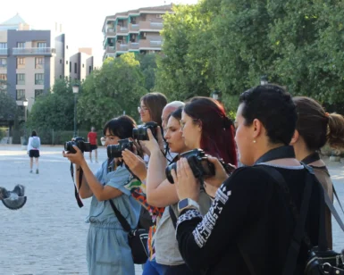 Un grupo captura momentos con "Taller de Fotografía en Granada: aprende a dominar tu cámara réflex", en medio de los árboles y edificios de Granada. - ForTwo - Planes para parejas
