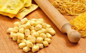 El Taller de Pasta Fresca en Sevilla y un fiel rodillo descansan sobre una superficie de madera, listos para preparar deliciosas comidas. - ForTwo - Planes para parejas