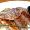 Los dumplings fritos, inspirados en los vibrantes sabores del Taller de cocina japonesa en Sevilla, se presentan en un plato blanco con una sabrosa salsa para mojar. - ForTwo - Planes para parejas