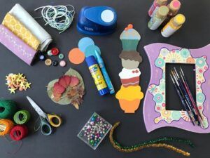 El producto "Talleres de Manualidades en Granada: Crea y Conecta con el Arte" ofrece materiales para manualidades como hilo, botones, pinturas y pinceles sobre una mesa que captura el espíritu artístico de Granada. - ForTwo - Planes para parejas