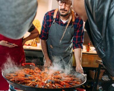 En Espai Granada, el chef cocina hábilmente una gran sartén de arroces humeantes durante los Talleres de cocina con arroces en Espai Granada, cautivando a los espectadores con el rico aroma y los colores vibrantes de los mariscos. - ForTwo - Planes para parejas