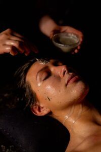 En el tranquilo y tenue ambiente de spa del Baño Turco con Café y Chocolate en Madrid, un huésped disfruta de un tratamiento facial con un delicado cepillo mientras sutiles aromas a chocolate impregnan el aire, evocando el ambiente reconfortante de una cafetería acogedora. - ForTwo - Planes para parejas