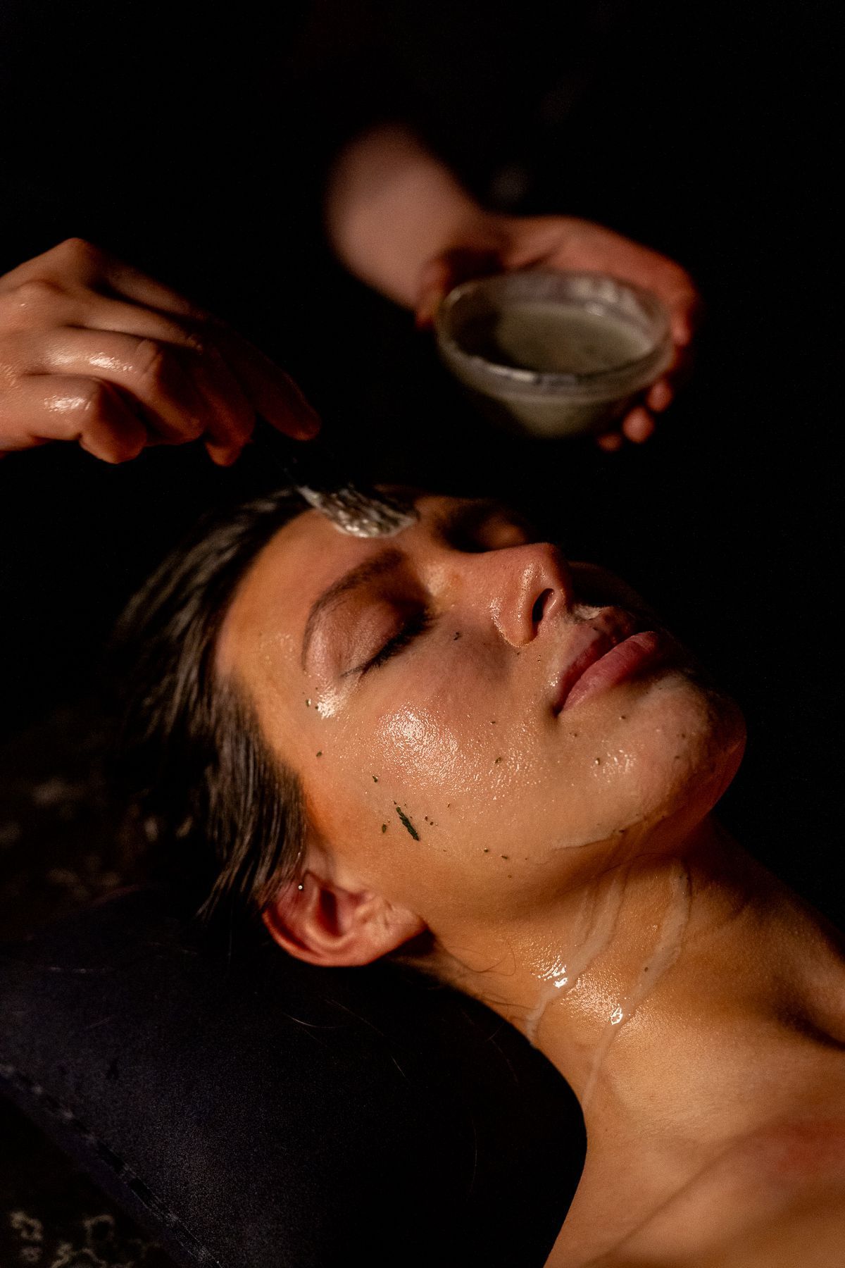 En el tranquilo y tenue ambiente de spa del Baño Turco con Café y Chocolate en Madrid, un huésped disfruta de un tratamiento facial con un delicado cepillo mientras sutiles aromas a chocolate impregnan el aire, evocando el ambiente reconfortante de una cafetería acogedora. - ForTwo - Planes para parejas