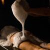 En una sala poco iluminada, una persona se relaja en una mesa, rodeada de relajantes burbujas durante un placentero masaje con espuma, que recuerda la experiencia de lujo que ofrece el Baño Turco con Café y Chocolate en Madrid. - ForTwo - Planes para parejas