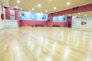 El espacioso estudio de baile, con piso de madera, espejos de pared y murales con temática de baile, es perfecto para practicar Tango o Ritmos Latinos en las "Clases de Baile de Salón en Madrid – Ritmos Latinos, Swing y Tango". - ForTwo - Planes para parejas