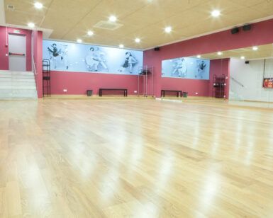 El espacioso estudio de baile, con piso de madera, espejos de pared y murales con temática de baile, es perfecto para practicar Tango o Ritmos Latinos en las "Clases de Baile de Salón en Madrid – Ritmos Latinos, Swing y Tango". - ForTwo - Planes para parejas