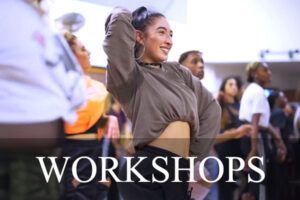 En un animado taller en Studio11, una persona baila alegremente Bachata con otros, vistiendo un top gris y pendientes de aro. - ForTwo - Planes para parejas