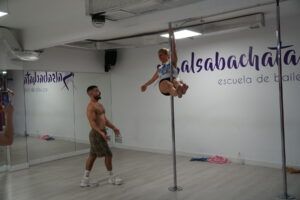 En un estudio de baile en Madrid, alguien cautiva a una audiencia con su fascinante rutina, mostrando el arte del pole dance como parte de Clases de Pole Dance en Madrid. - ForTwo - Planes para parejas