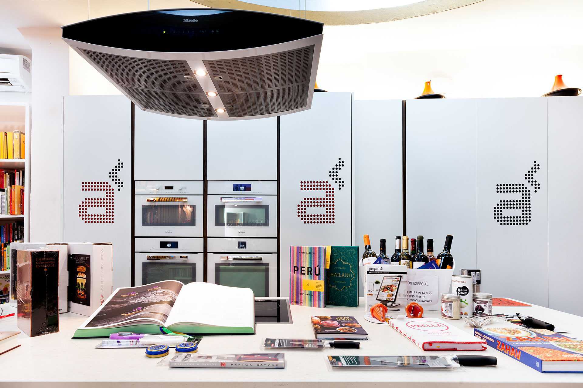 Una cocina moderna en Madrid cuenta con elegantes electrodomésticos con una encimera repleta de libros de cocina y productos gourmet Diviértete Cocinando en Madrid A Punto, perfectos para preparar deliciosos platos combinados con buen vino. - ForTwo - Planes para parejas