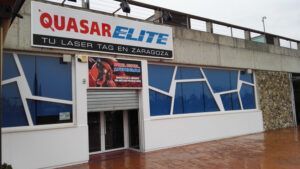 El Laser Tag en Zaragoza con Quasar Elite presenta un exterior deslumbrante con diseños geométricos de ventanas que se reflejan en el suelo mojado, invitando a los amantes de las emociones fuertes a una aventura de laser tag inolvidable. - ForTwo - Planes para parejas