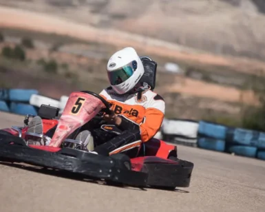 Vestido con mono de carreras y casco, un piloto maniobra con destreza el kart número 5 por la pista en ¡Acelera en el Karting de Mozota en Zaragoza!. - ForTwo - Planes para parejas