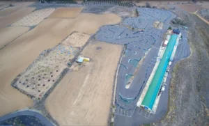Vista aérea de ¡Acelera en el Karting de Mozota en Zaragoza!, con sinuosos circuitos de carreras y un largo edificio con techo verde, situado junto a campos abiertos. - ForTwo - Planes para parejas