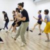 Los participantes practican con entusiasmo movimientos sincronizados de Lindy Hop sobre un suelo de madera con ropa cómoda en el estudio "Aprende a Bailar Swing en Huesca: Clases de Lindy Hop para Todos los Niveles". - ForTwo - Planes para parejas