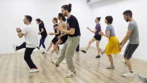 Los participantes practican con entusiasmo movimientos sincronizados de Lindy Hop sobre un suelo de madera con ropa cómoda en el estudio "Aprende a Bailar Swing en Huesca: Clases de Lindy Hop para Todos los Niveles". - ForTwo - Planes para parejas