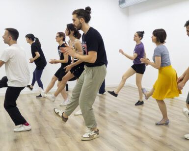 Los participantes practican con entusiasmo movimientos sincronizados de Lindy Hop sobre un suelo de madera con ropa cómoda en el estudio "Aprende a Bailar Swing en Huesca: Clases de Lindy Hop para Todos los Niveles". - ForTwo - Planes para parejas