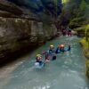 Tres buscadores de emociones con cascos caminan alegremente por un arroyo rocoso, disfrutando del Barranquismo en Huesca para Principiantes con Anayet Aventura en medio de los impresionantes paisajes de Huesca. - ForTwo - Planes para parejas