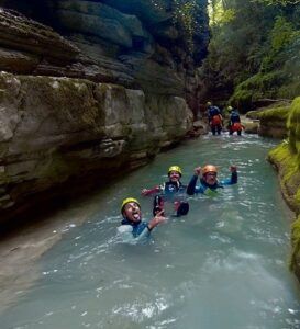Tres buscadores de emociones con cascos caminan alegremente por un arroyo rocoso, disfrutando del Barranquismo en Huesca para Principiantes con Anayet Aventura en medio de los impresionantes paisajes de Huesca. - ForTwo - Planes para parejas