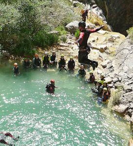 Una persona con traje de neopreno salta desde un saliente rocoso a una poza ante la mirada cautivada de los espectadores. Experimenta la emoción del Barranquismo en Huesca para Principiantes con Anayet Aventura, capturando el espíritu aventurero de Huesca. - ForTwo - Planes para parejas