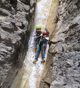 Entre acantilados rocosos, una persona desciende en rápel por una estrecha cascada con casco y equipo como parte de la experiencia "Barranquismo en Huesca para Principiantes" de Anayet Aventura en paisajes impresionantes. - ForTwo - Planes para parejas