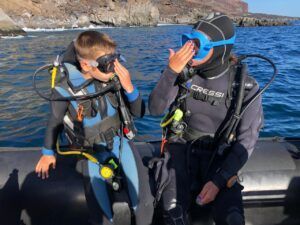 Cerca de las costas rocosas de El Hierro, un niño y un adulto se ajustan las máscaras antes de comenzar el Bautismo de Buceo en El Hierro: Vive tu Primera Inmersión. - ForTwo - Planes para parejas