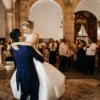 Los novios, alegres en su Clase Particular de Baile para Novios en Madrid, bailaron con gracia en el elegante recinto con arcos de piedra, observados con admiración por sus invitados. - ForTwo - Planes para parejas