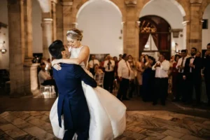 Los novios, alegres en su Clase Particular de Baile para Novios en Madrid, bailaron con gracia en el elegante recinto con arcos de piedra, observados con admiración por sus invitados. - ForTwo - Planes para parejas