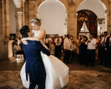Los novios, alegres en su Clase Particular de Baile para Novios en Madrid, bailaron con gracia en el elegante recinto con arcos de piedra, observados con admiración por sus invitados. - ForTwo - Planes para parejas