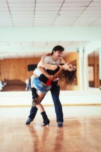 En Monzón, una pareja baila enérgicamente Salsa Cubana sobre pisos de madera en un estudio bien iluminado durante las Clases de Baile Latino: Salsa Cubana, Bachata y Merengue. - ForTwo - Planes para parejas
