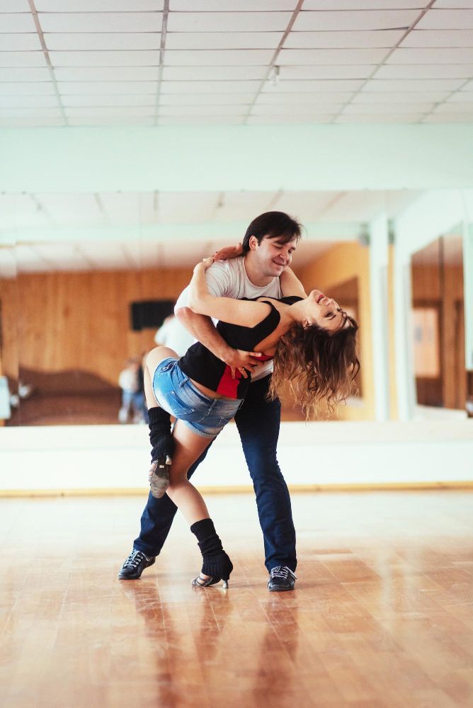 En Monzón, una pareja baila enérgicamente Salsa Cubana sobre pisos de madera en un estudio bien iluminado durante las Clases de Baile Latino: Salsa Cubana, Bachata y Merengue. - ForTwo - Planes para parejas