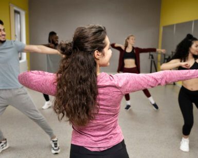 En un animado estudio de paredes grises y amarillas, la gente irradia alegría mientras se estira y se mueve en sus Clases de Salsa en Huesca: Aprende a Bailar con Ritmo y Pasión. - ForTwo - Planes para parejas