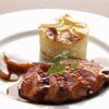 El pato asado en rodajas con salsa, servido elegantemente junto con un gratinado de patatas en capas y guarnición de perejil, parece un plato del "Curso de Cocina Francesa: Descubre el Arte Culinario con Mélanie Dyé". - ForTwo - Planes para parejas