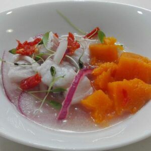 Un tazón blanco presenta elegantemente un ceviche con camote anaranjado cortado en cubitos, cebolla roja y microvegetales, un plato que podría inspirar a cualquier chef en el Curso de Cocina para Principiantes: Saca al Chef que Lleva Dentro. - ForTwo - Planes para parejas
