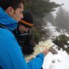 Dos personas con ropa de invierno se encuentran en un sendero nevado y brumoso en Huesca, participando en el Curso de Orientación en Montaña con Mapa y Brújula para una navegación precisa. - ForTwo - Planes para parejas