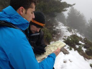 Dos personas con ropa de invierno se encuentran en un sendero nevado y brumoso en Huesca, participando en el Curso de Orientación en Montaña con Mapa y Brújula para una navegación precisa. - ForTwo - Planes para parejas