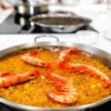 La paella de mariscos con langostinos, cocinada a la perfección, despierta al chef que llevas dentro. Con los sabores de un plato clásico, es como experimentar "¡Cursos de Cocina: ¡Despierta al Chef que Lleva Dentro!" en la comodidad de tu cocina. - ForTwo - Planes para parejas