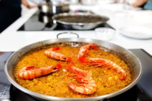La paella de mariscos con langostinos, cocinada a la perfección, despierta al chef que llevas dentro. Con los sabores de un plato clásico, es como experimentar "¡Cursos de Cocina: ¡Despierta al Chef que Lleva Dentro!" en la comodidad de tu cocina. - ForTwo - Planes para parejas
