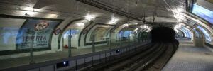 Una antigua estación de metro con paredes de azulejos y anuncios evoca el encanto de "Descubre la Estación Fantasma de Chamberí: Un Viaje al Madrid de los Años 20". - ForTwo - Planes para parejas