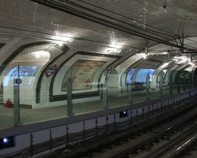 Una antigua estación de metro con paredes de azulejos y anuncios evoca el encanto de "Descubre la Estación Fantasma de Chamberí: Un Viaje al Madrid de los Años 20". - ForTwo - Planes para parejas