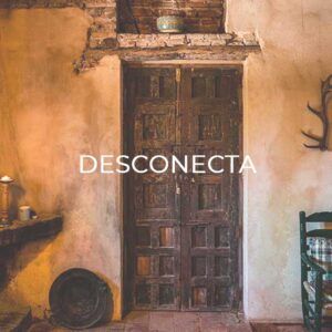 La Escapada "Desconecta": Relax y Bienestar en Córdoba cuenta con una puerta rústica con el texto "Desconecta", tonos cálidos y el encanto cordobés. Astas adornan la pared, mientras que una silla a la derecha invita a la relajación y el bienestar. - ForTwo - Planes para parejas
