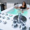 Dos mujeres se entregan a una Experiencia de Relax en Pareja, cada una en su bañera separada llena de agua burbujeante, saboreando la paz de un spa moderno. - ForTwo - Planes para parejas