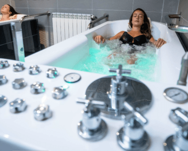 Dos mujeres se entregan a una Experiencia de Relax en Pareja, cada una en su bañera separada llena de agua burbujeante, saboreando la paz de un spa moderno. - ForTwo - Planes para parejas