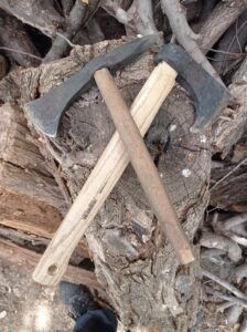 Dos hachas con mangos de madera cruzadas sobre una pila de troncos muestran el arte de "Forja Tu Propia Hacha: Una Experiencia Única". - ForTwo - Planes para parejas