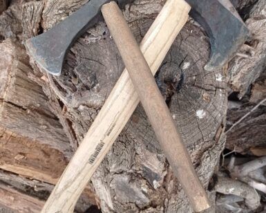 Dos hachas con mangos de madera cruzadas sobre una pila de troncos muestran el arte de "Forja Tu Propia Hacha: Una Experiencia Única". - ForTwo - Planes para parejas