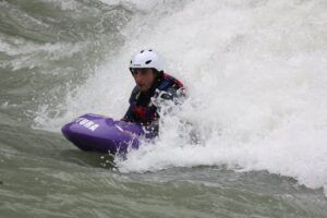 Con un casco puesto, alguien maniobra expertamente una tabla fluvial sobre las agitadas aguas blancas, abrazando el emocionante Hidrospeed en Huesca: Descenso de Aventura en el Río para Amantes de la Adrenalina. - ForTwo - Planes para parejas