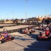 Los corredores en karts individuales recorren una pista al aire libre rodeada de barreras de neumáticos bajo un cielo despejado, encarnando la emoción del karting con "Karting en Jaca: Karts Individuales, Biplaza y Junior para Toda la Familia. - ForTwo - Planes para parejas