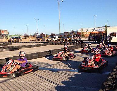 Los corredores en karts individuales recorren una pista al aire libre rodeada de barreras de neumáticos bajo un cielo despejado, encarnando la emoción del karting con "Karting en Jaca: Karts Individuales, Biplaza y Junior para Toda la Familia. - ForTwo - Planes para parejas