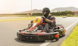 Vestido con un casco y un traje negros, el conductor maniobra hábilmente el kart de Karting en Tenerife Sur contra el emocionante telón de fondo de las montañas de Los Cristianos. - ForTwo - Planes para parejas